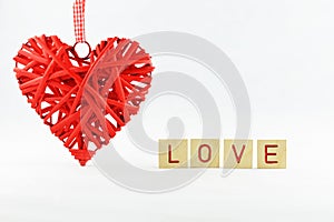 beautiful red wicker heart with a white background with letters inscription love