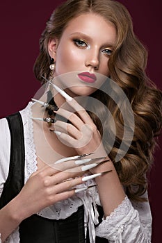 Beautiful redhair model: curls, bright gold makeup, long nails and red lips. The beauty face. Manicure disign