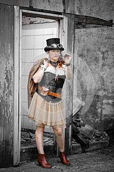 Beautiful redhair steampunk girl with goggles on black hat outside toilet background. Old-fashioned