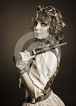 Beautiful redhair steampunk girl with gun looking at camera. Old