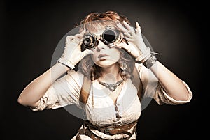 Beautiful redhair steampunk girl looking over her goggles aside photo