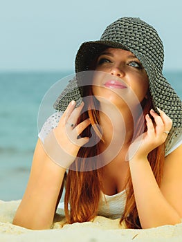 Beautiful redhaired girl in hat on beach, portrait