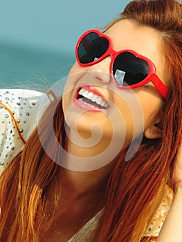 Beautiful redhaired girl in sunglasses on beach, portrait