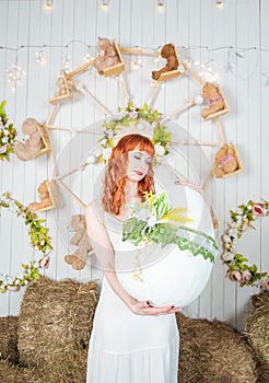 Beautiful redhaired woman with big egg toy standing on the haystack Easter holiday concept