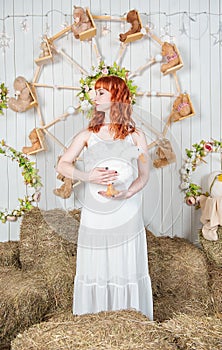 Beautiful redhaired woman with goose toy standing on the haystack Easter holiday concept