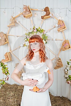 Beautiful redhaired woman with goose toy standing on the haystack Easter holiday concept