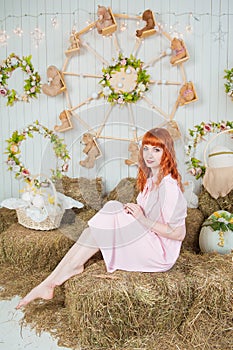 Beautiful redhaired woman sitting on the haystack Easter holiday concept