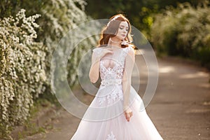 Beautiful redhead Bride in fantastic wedding dress in blooming garden.