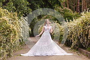 Beautiful redhead Bride in fantastic wedding dress in blooming garden.