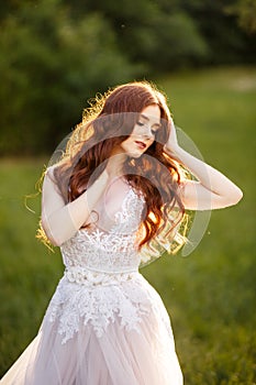 Beautiful redhead Bride in fantastic wedding dress in blooming garden.