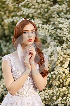 Beautiful redhead Bride in fantastic wedding dress in blooming garden.