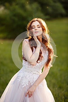 Beautiful redhead Bride in fantastic wedding dress in blooming garden.