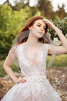 Beautiful redhead Bride in fantastic wedding dress in blooming garden.