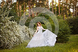 Beautiful redhead Bride in fantastic wedding dress in blooming garden.