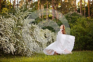 Beautiful redhead Bride in fantastic wedding dress in blooming garden.