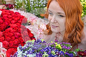 Beautiful redhead Caucasian girl smelling colorful flowers