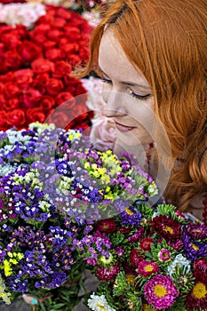 Beautiful redhead Caucasian girl smelling colorful flowers