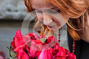 Beautiful redhead Caucasian girl smelling colorful flowers in the garden