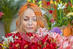 Beautiful redhead Caucasian girl smelling colorful flowers in the garden