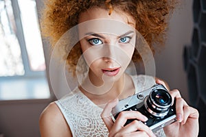 Beautiful redhead curly young woman photographer with vintage camera