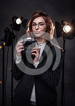 Beautiful redhead female photographer holds a digital camera and looking on the camera