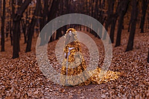 Beautiful redhead girl as an autumn in leaf cloak in forest background beauty portrait photoshoot