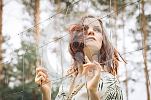 Beautiful redhead girl behind fence outdoors.