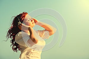 Beautiful redhead girl enjoys music, headphon