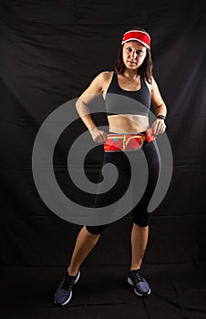 Beautiful redhead girl in jogging uniform posing in studio on black background