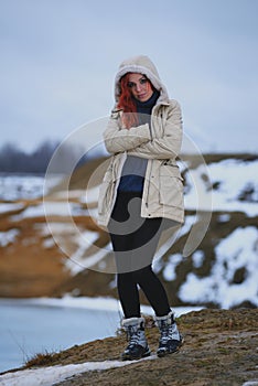 Beautiful redhead girl stays against Nordic landscape