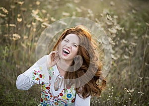 Beautiful redhead laughs in a field of wildflowers outdoors in Texas