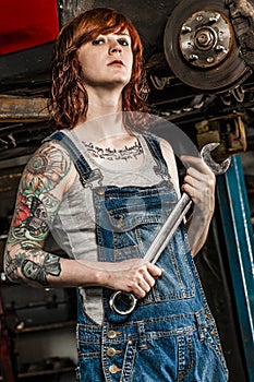 Beautiful redhead mechanic fixing brakes