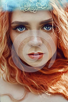 Beautiful redhead Norwegian girl with big eyes and freckles on face in the forest. Portrait of redhead woman closeup in nature