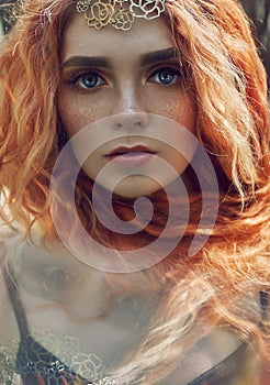 Beautiful redhead Norwegian girl with big eyes and freckles on face in the forest. Portrait of redhead woman closeup in nature