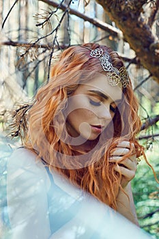 Beautiful redhead Norwegian girl with big eyes and freckles on face in the forest. Portrait of redhead woman closeup in nature