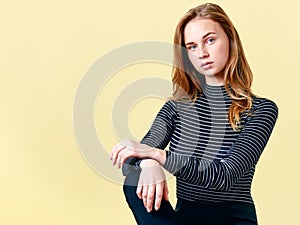 Beautiful redhead teenager with freckles posing for fashion portrait, pastel colours background. Gorgeous young woman