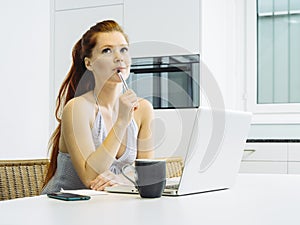 Beautiful redhead using laptop at home