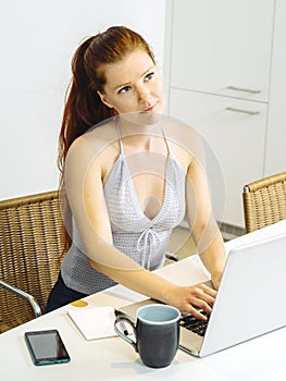 Beautiful redhead using laptop in the kitchen