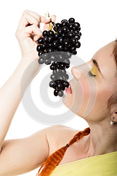 Beautiful redhead woman is eating black grapes. concept of healthy eating