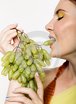 Beautiful redhead woman is eating grapes. concept of healthy eating