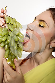 Beautiful redhead woman is eating grapes. concept of healthy eating