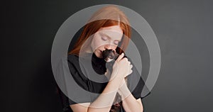 beautiful redhead woman holds little ferret in her arms, stroking and hugging it
