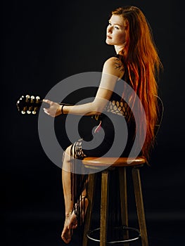 Beautiful redhead woman playing acoustic guitar