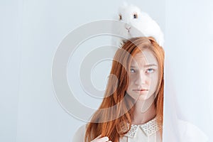 Beautiful redhead woman posing with rabbit on her head