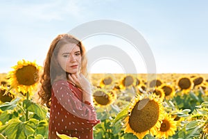 Beautiful redhead woman in sunflower field on sunny day