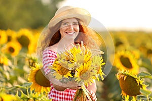 Beautiful redhead woman in sunflower field on sunny day