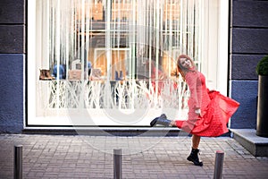 Beautiful redhead woman wearing red dress and stylish coat on city street. loneliness and depression concept