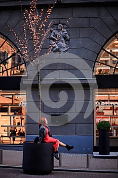 Beautiful redhead woman wearing red dress and stylish coat on city street. loneliness and depression concept