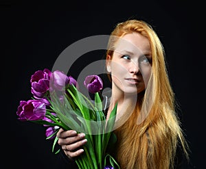 Beautiful redheaded girl hold bouquet of purple tulips flowers