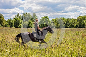 Beautiful redheaded girl riding a horse in countryside. .